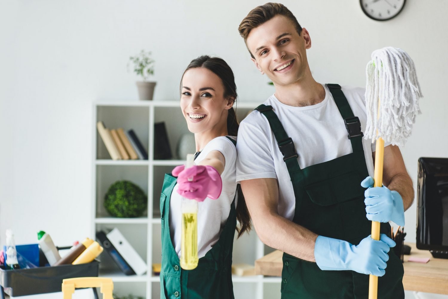 happy-young-cleaners-with-mop-and-spray-bottle-smiling-at-camera-while-cleaning-office-e1616490852654.jpg